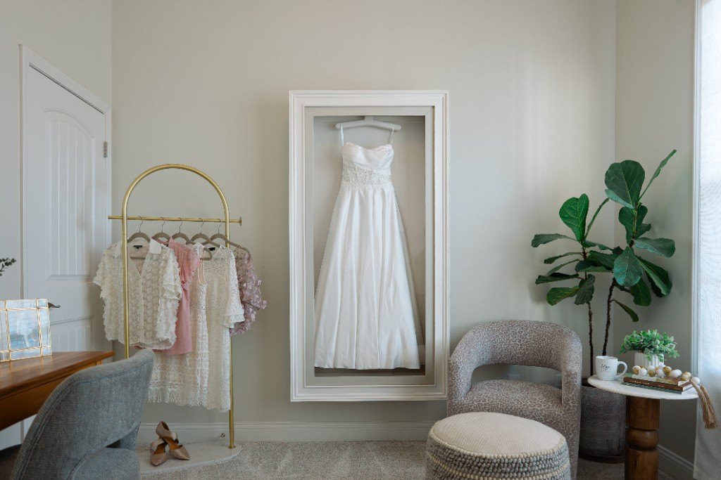 A wall-mounted Mrs. Case Gallery displaying a satin gown in a dressing room