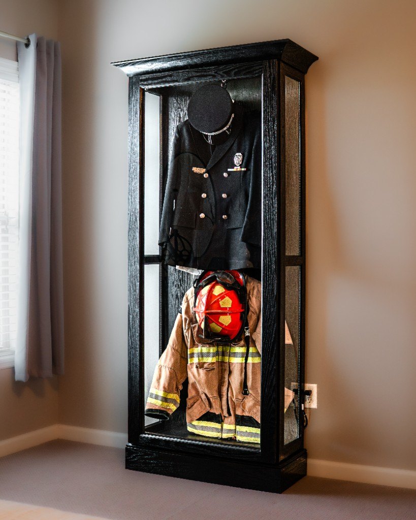A freestanding Mrs. Case displaying a dress uniform and firefighter gear