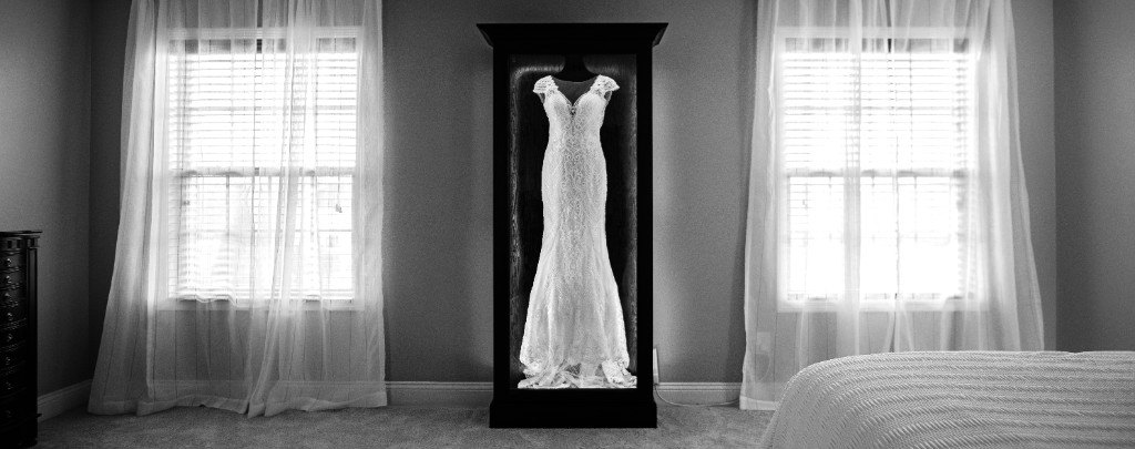 A freestanding Mrs. Case Signature displaying a lace gown between two windows in a bedroom