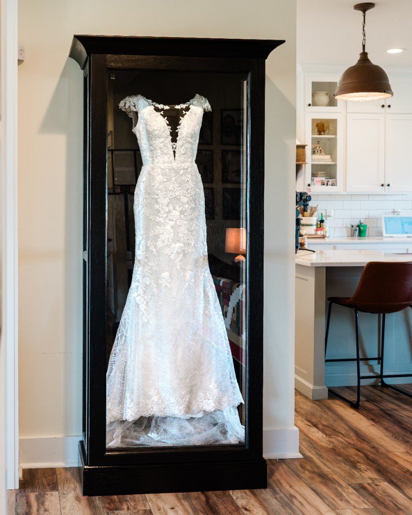 A freestanding Mrs. Case Signature displaying a lace gown beside a kitchen