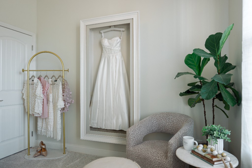 A strapless satin gown hanging inside a wall-mounted Mrs. Case Gallery in a dressing room